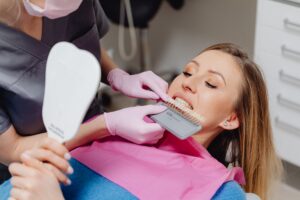 Dentist discussing professional teeth whitening with a patient while comparing tooth shades to determine the most appropriate cosmetic treatment.
